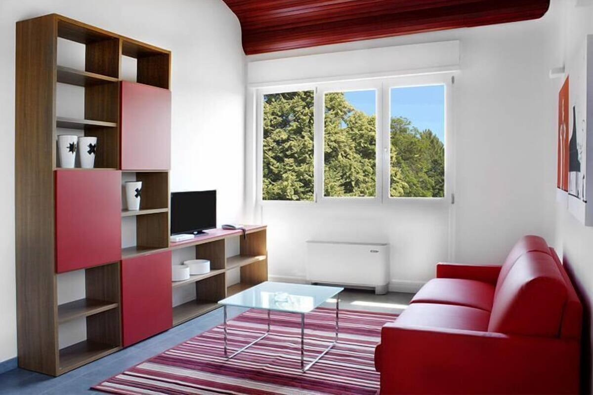 A modern living room with a red sofa, a glass coffee table, and a red and white bookshelf.