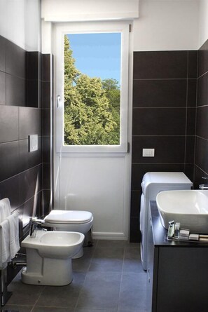 A compact bathroom with two toilets, a bidet, and a sink.