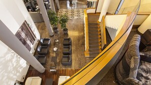 Un hallo espacioso con una escalera, zona de estar y plantas en macetas.