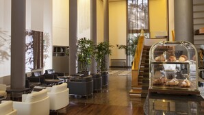 Un vestíbulo moderno con zonas de estar, exhibición de café y una escalera.