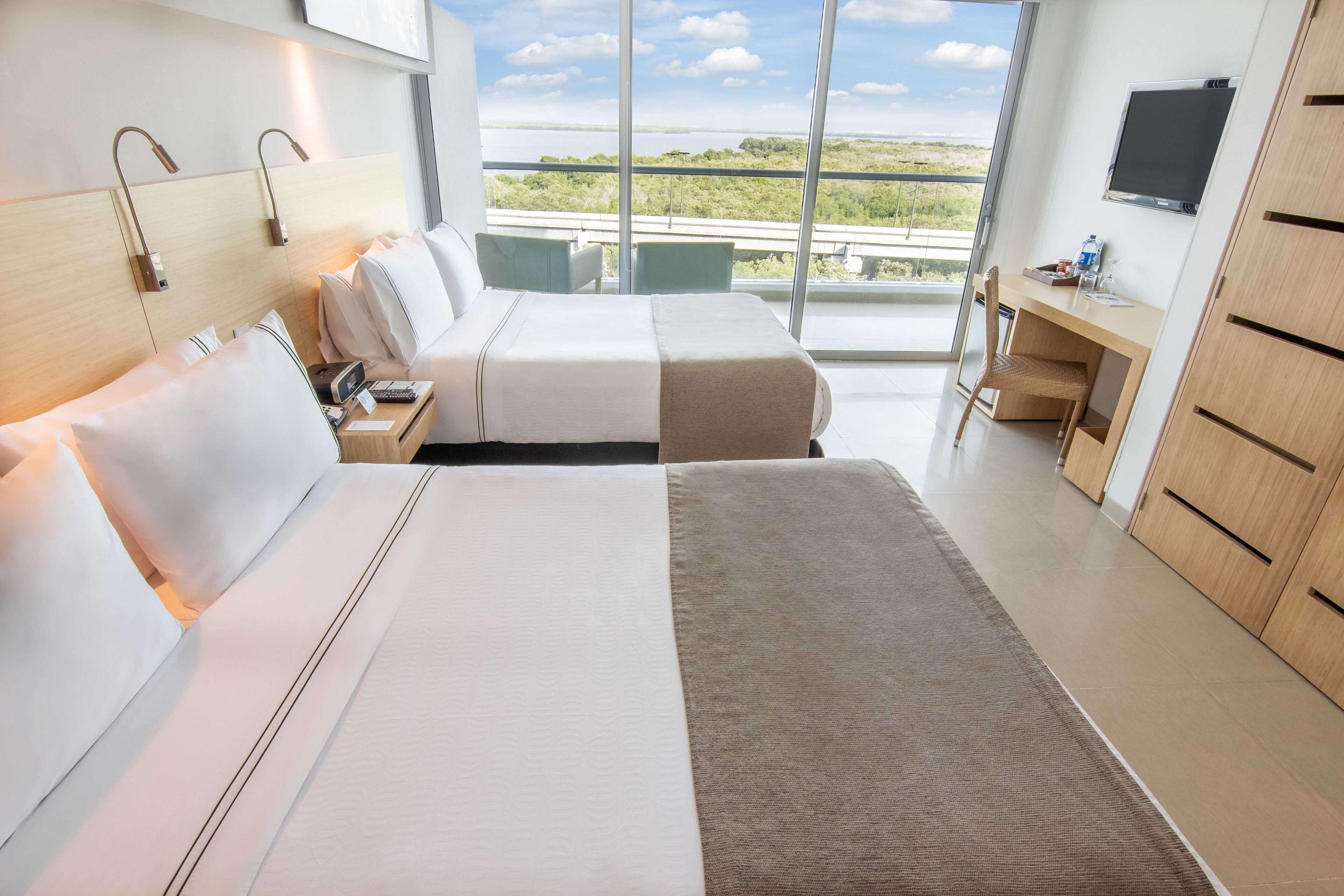 Camera d'albergo con un letto grande, una scrivania, una sedia e una TV. La stanza offre vista sull'esterno.