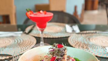 A dining table with a bowl of food and a cocktail.