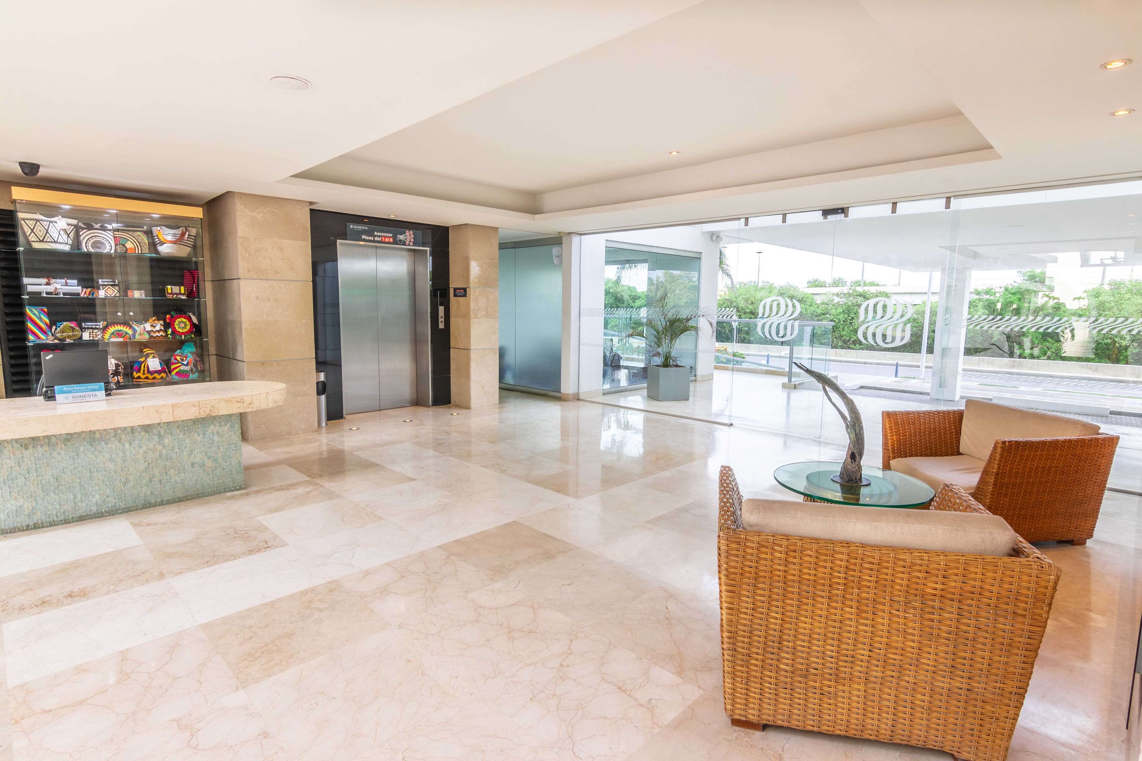 A lobby with a reception desk, a glass sculpture, wicker furniture, and a view of the outdoors.