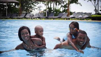 Alberca al aire libre, sombrillas en la alberca y camastros