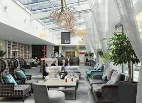 Un salón amplio con barra, diferentes disposiciones de asientos y una gran estantería.