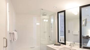 A modern bathroom with a glass-enclosed shower, a large bathtub, and a vanity with two sinks.