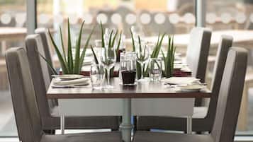 A dining table set with chairs, clear glasses, and a small potted plant.
