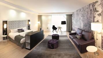 Una habitación de hotel moderna con una cama grande, un escritorio, un sofá y un comedor.
