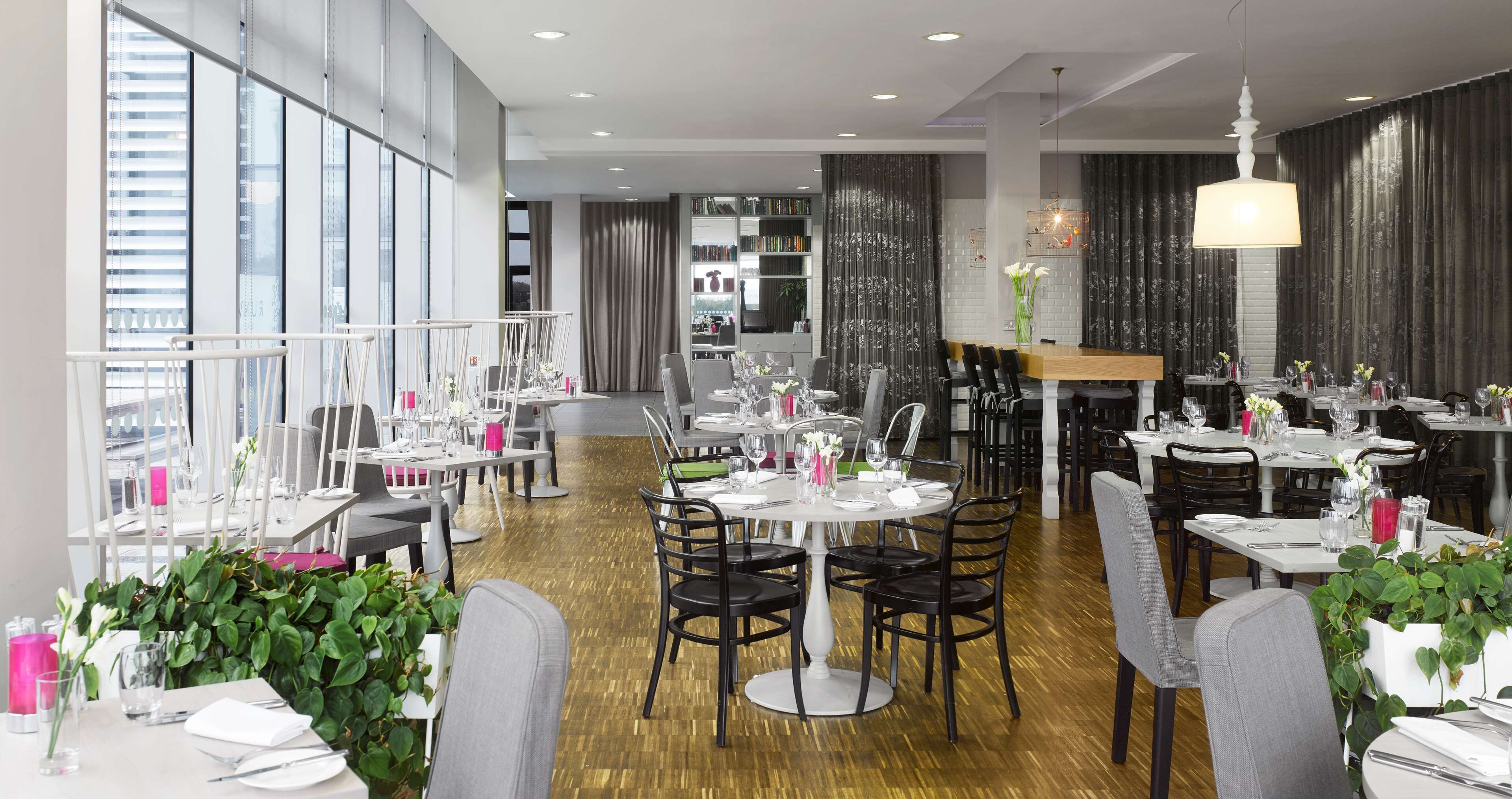 Un restaurante moderno con mesas redondas, sillas negras y una decoración que combina blanco y tonos oscuros.