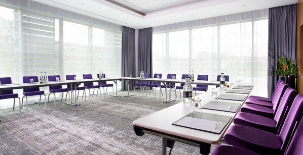 A conference room with a long table, purple chairs, and large windows.