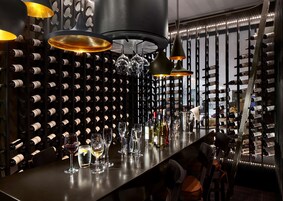 Zona de bar con botelleros, copas y botellas.