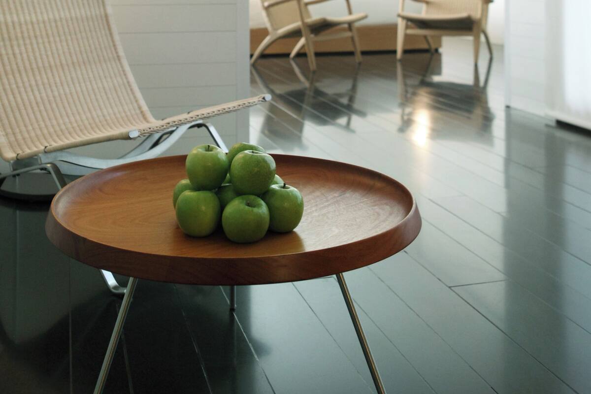 A modern room with a round wooden table, a chair, and a lamp.