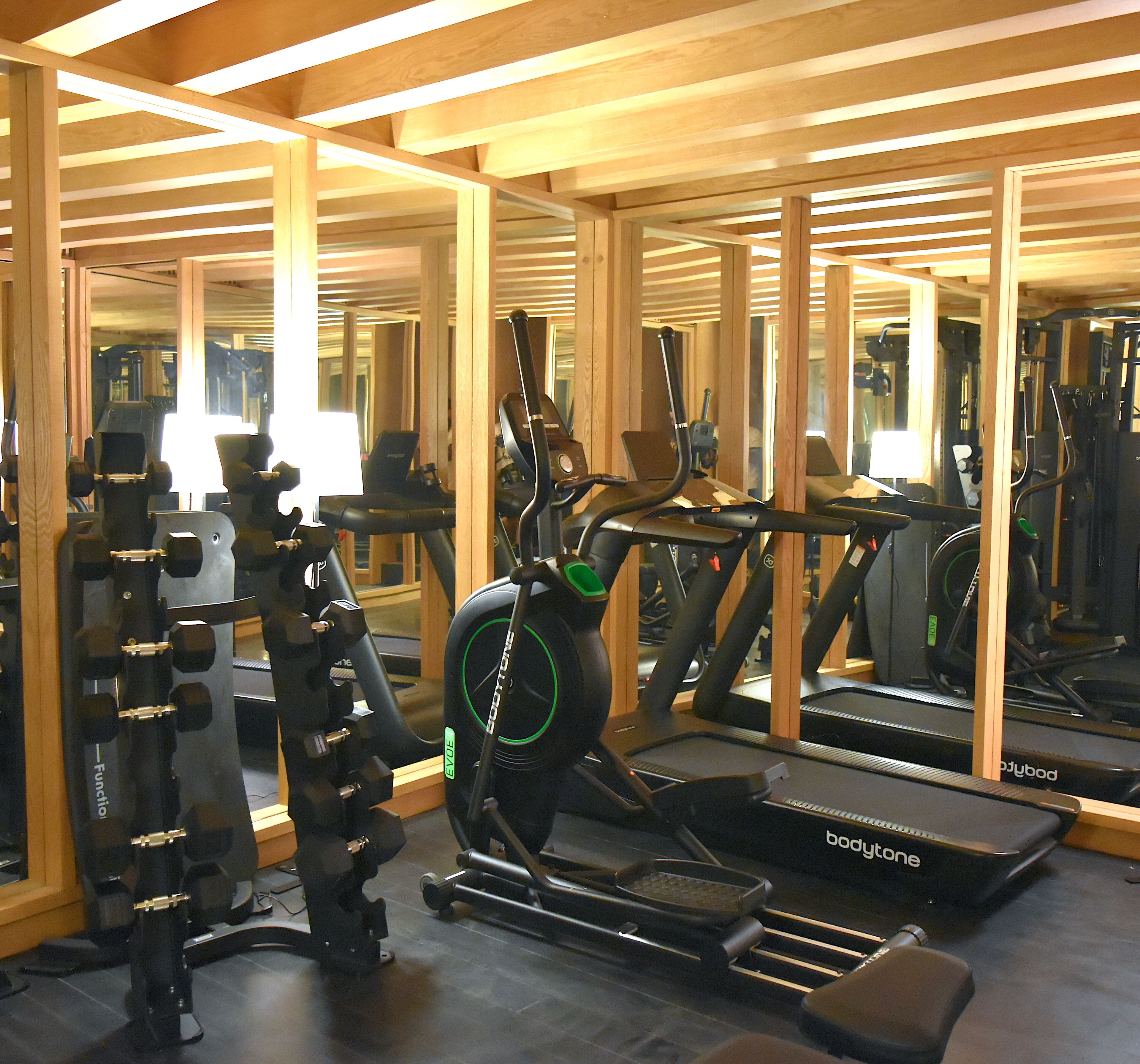 Un gimnasio con equipo de ejercicio, vigas de madera y espejos.