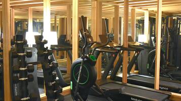 Un gimnasio con equipo de ejercicio, vigas de madera y espejos.