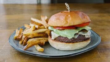Un plato con una hamburguesa y papas fritas sobre una mesa de madera.