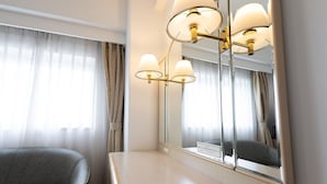Een hotelkamer met een grote spiegel, een nachtkastje, een stoel en gordijnen.