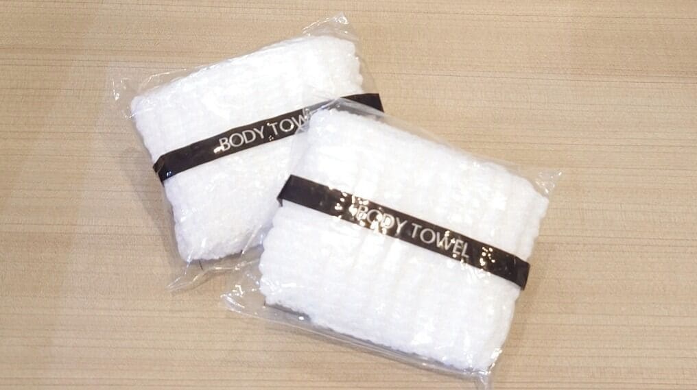 Two white towels with black text on them, placed on a wooden surface.