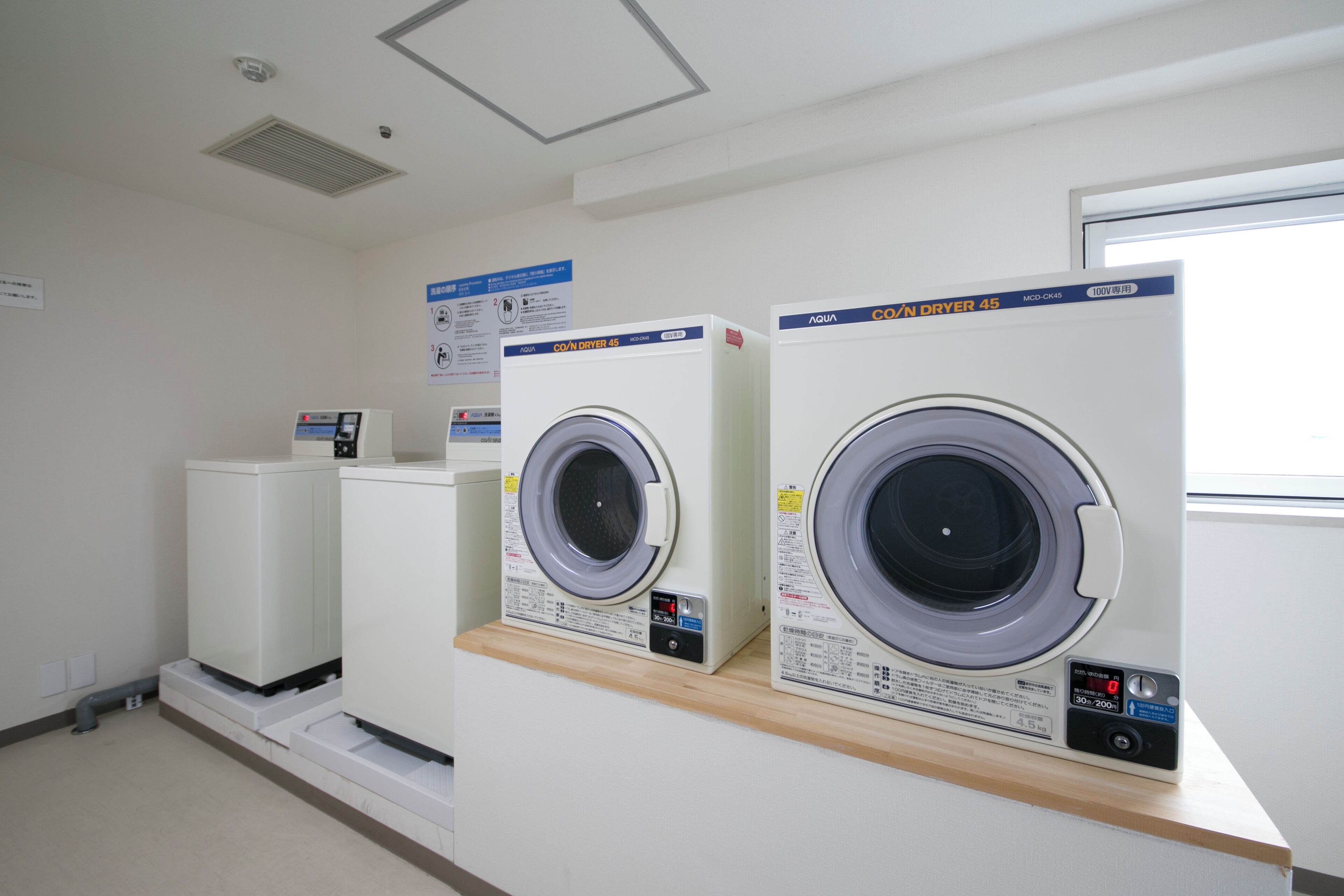 A laundry facility with two front-loading washing machines and a dryer.