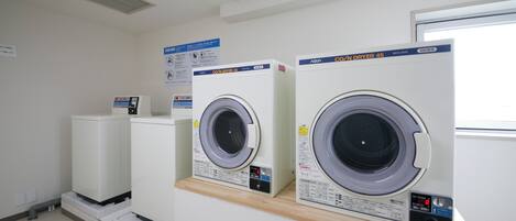 A laundry facility with two front-loading washing machines and a dryer.