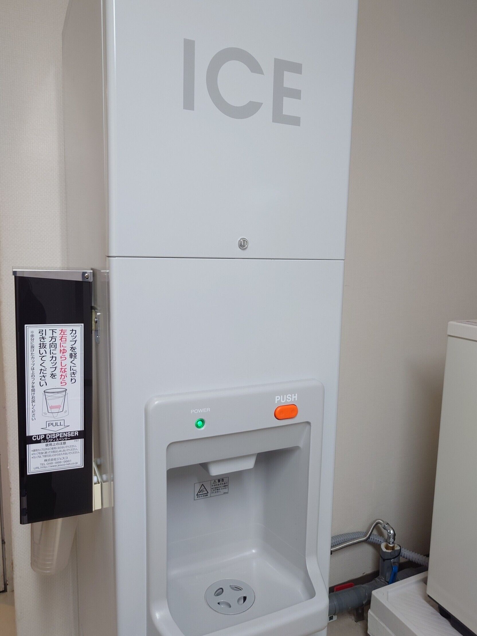 Habitación de hotel con dispensador de hielo de pared y dispensador de vasos.
