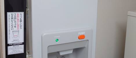 Habitación de hotel con dispensador de hielo de pared y dispensador de vasos.