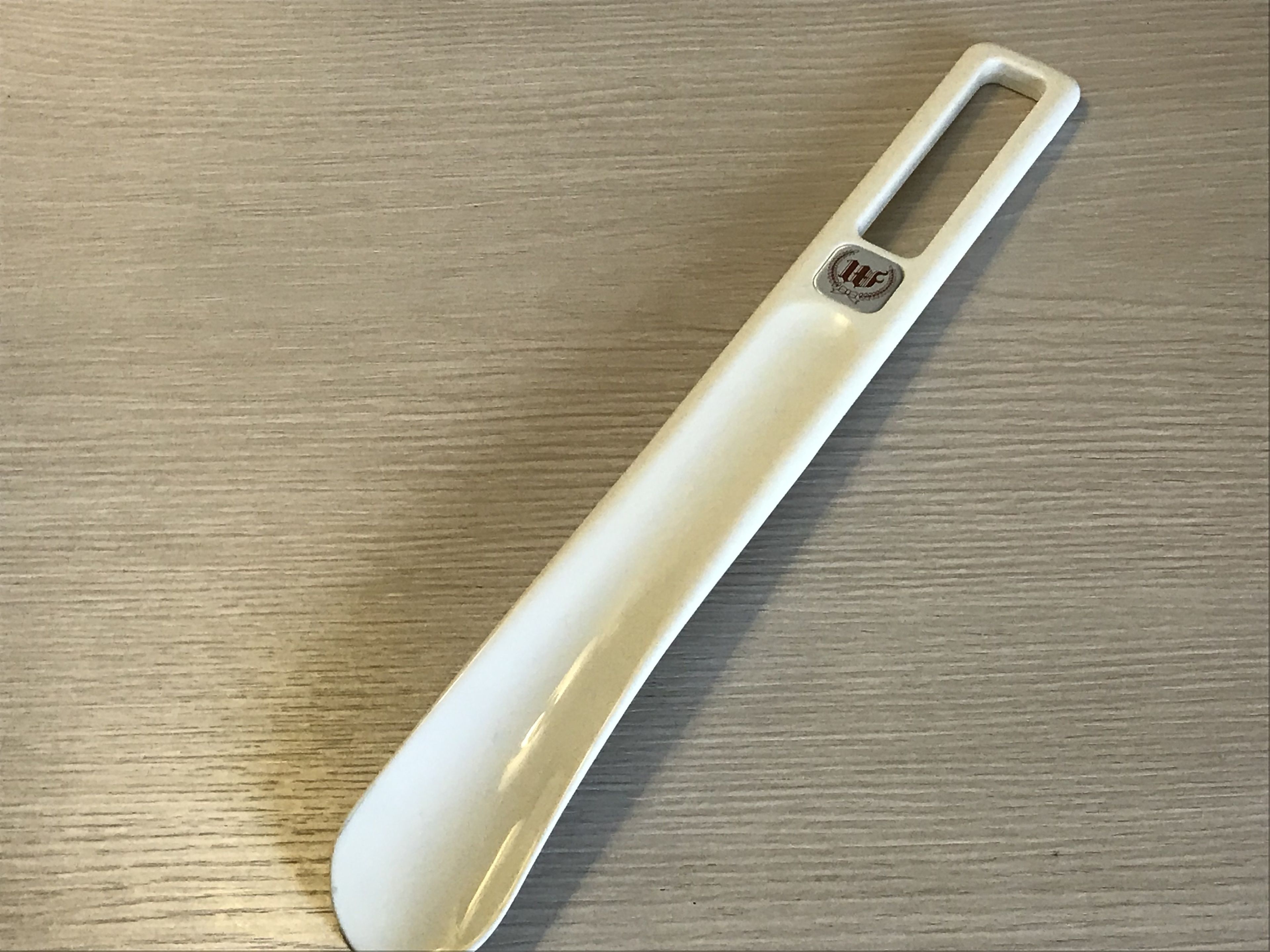 A white object with a handle and a logo on a wooden surface.