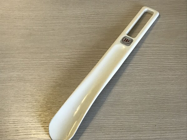 Un objeto blanco con asa y un logotipo sobre una superficie de madera.