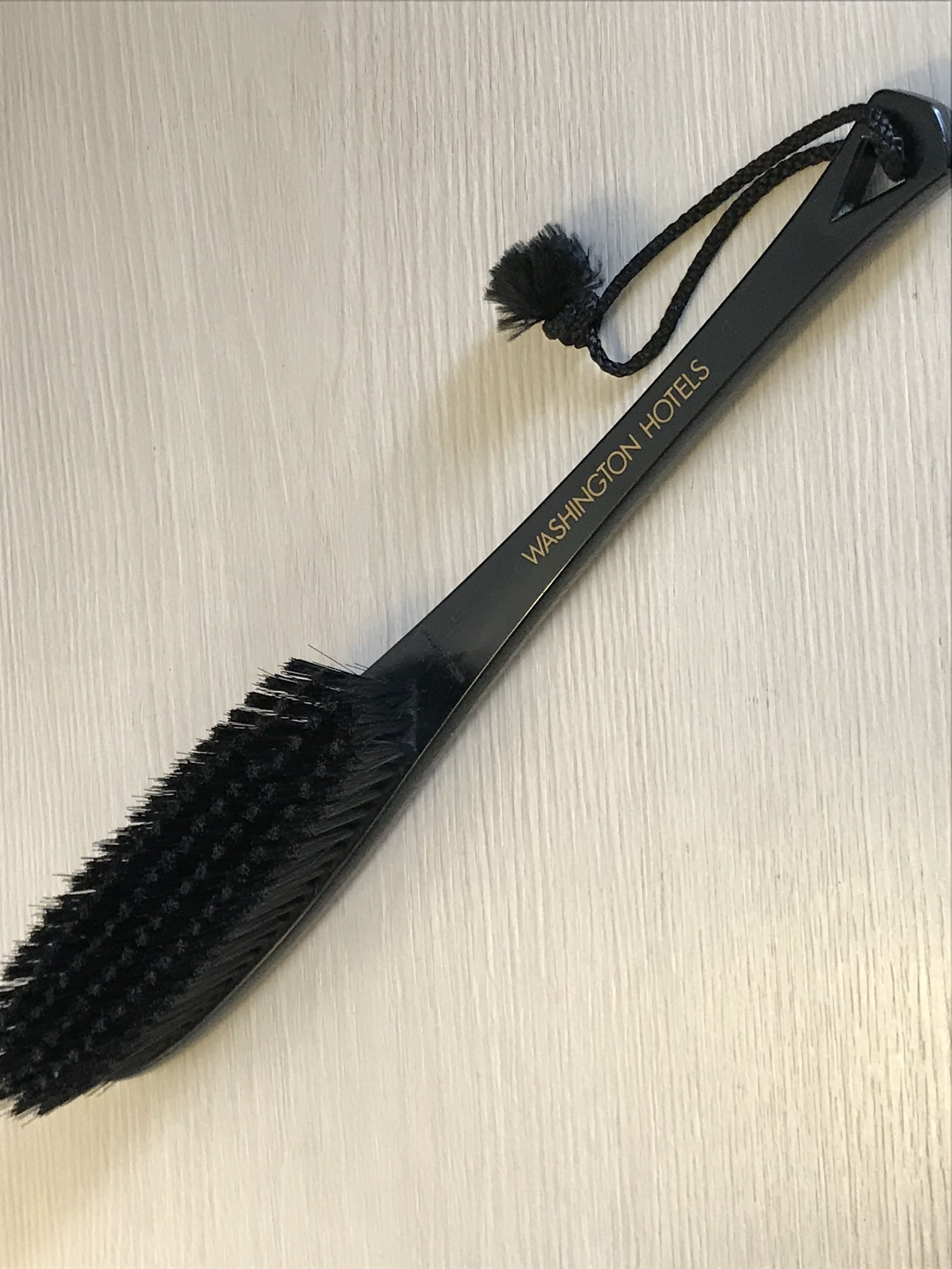 Un cepillo de pelo negro con borla, con la etiqueta "Washington Hotels".