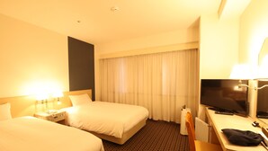 Habitación de hotel con dos camas, un escritorio con televisor y una silla.