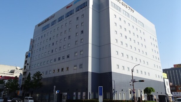 Un hotel de varios pisos con un diseño moderno, que presenta una entrada destacada en esquina y varias ventanas en cada planta.