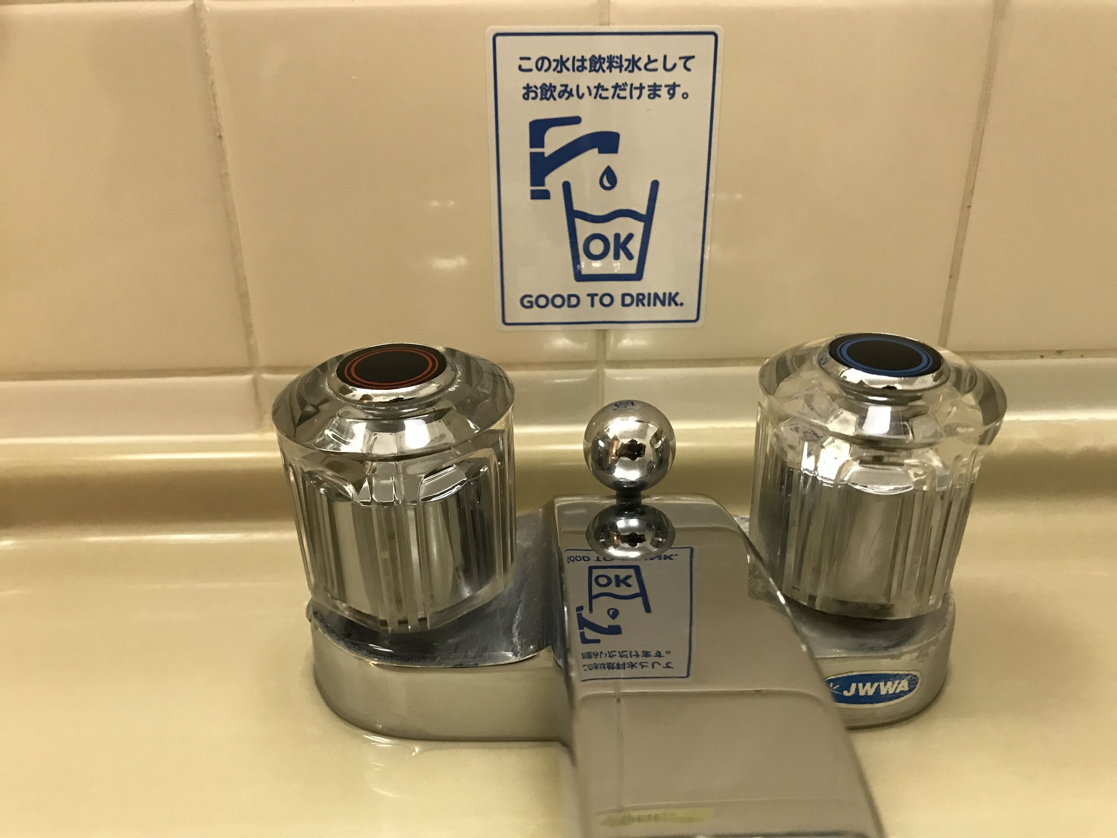 A bathroom sink with two water dispensers and a sign indicating the water is safe to drink.