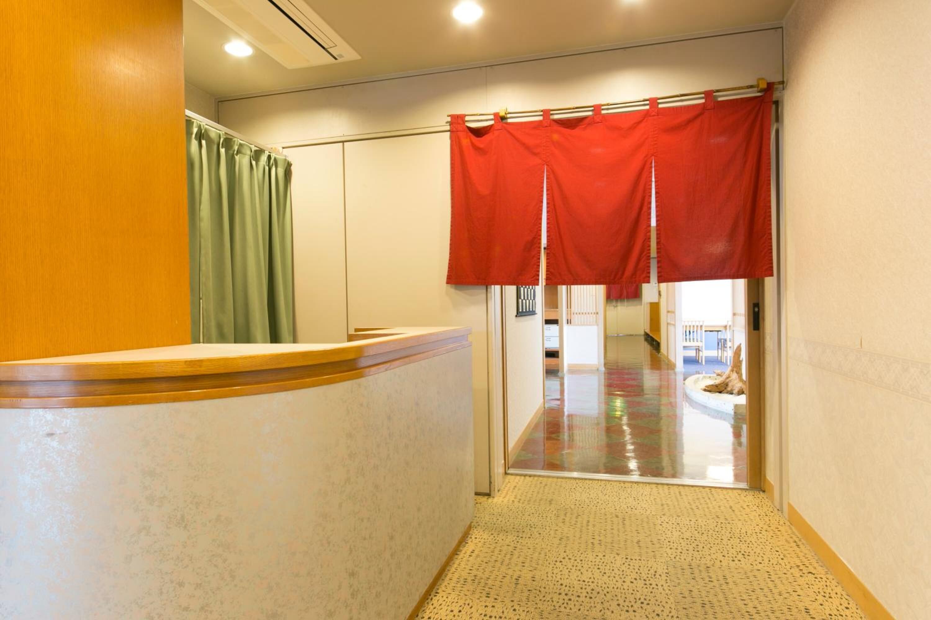 A hotel reception area with a reception desk, a green curtain, and a red curtain.