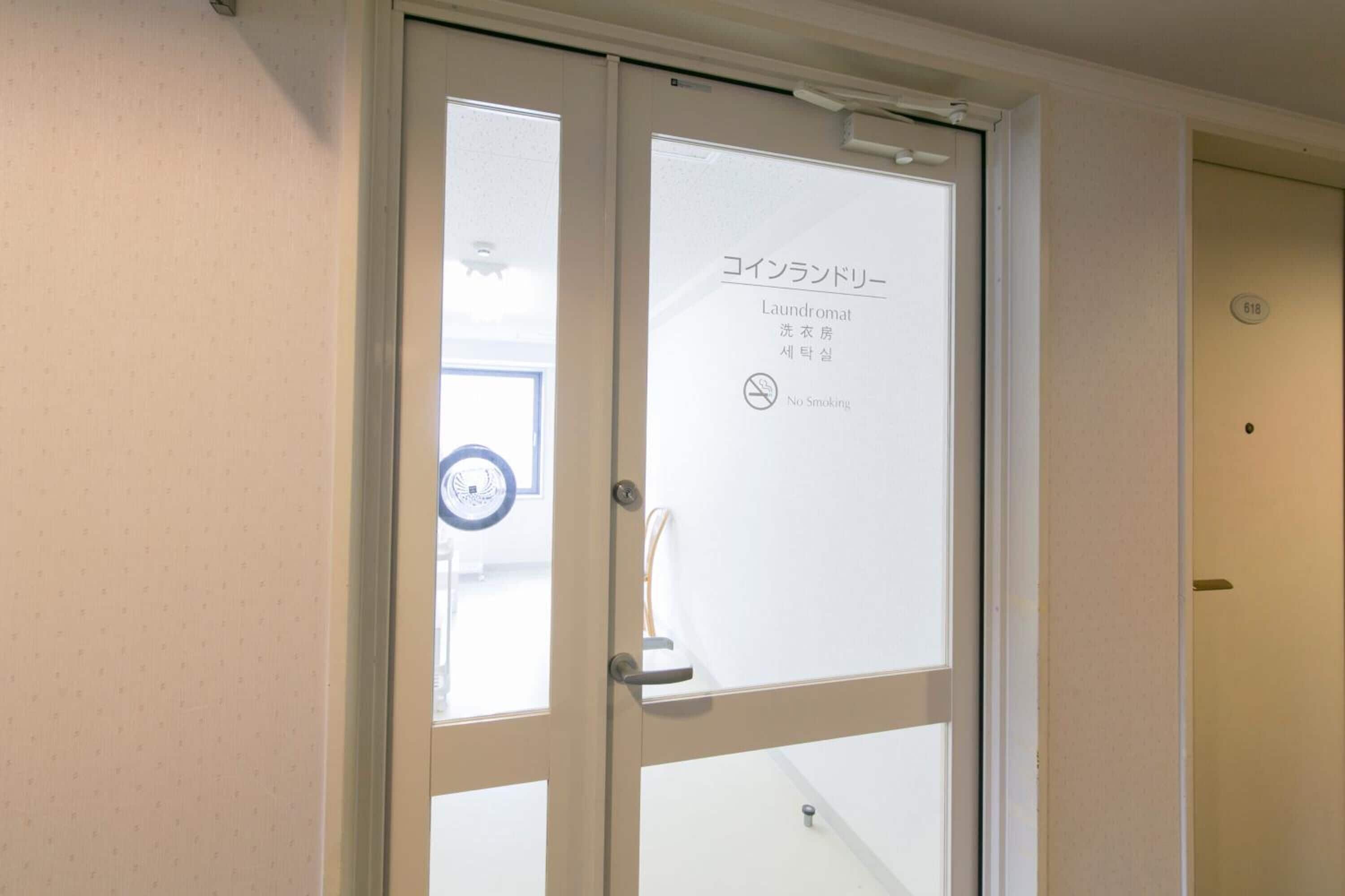 A hotel room door with a frosted glass panel displaying text in multiple languages, including English, Japanese, and Korean.