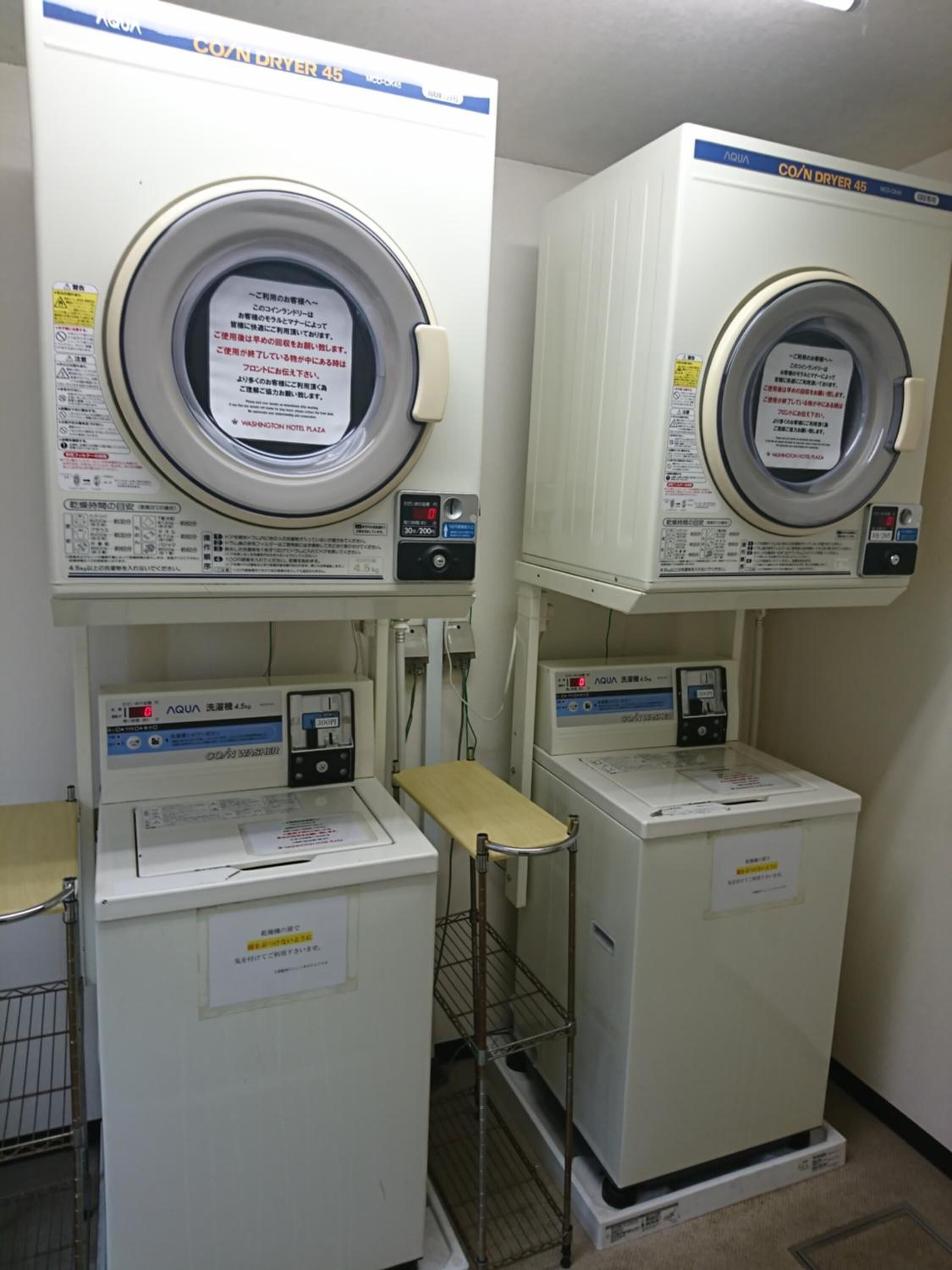 Two front-loading washing machines with control panels, a metal shelf, and a metal ladder.