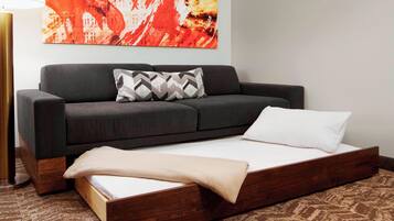 A room with a bed, a sofa, and a large abstract painting on the wall.
