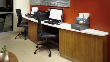 Una mesa de recepción con dos computadoras, una impresora y una estación de café.