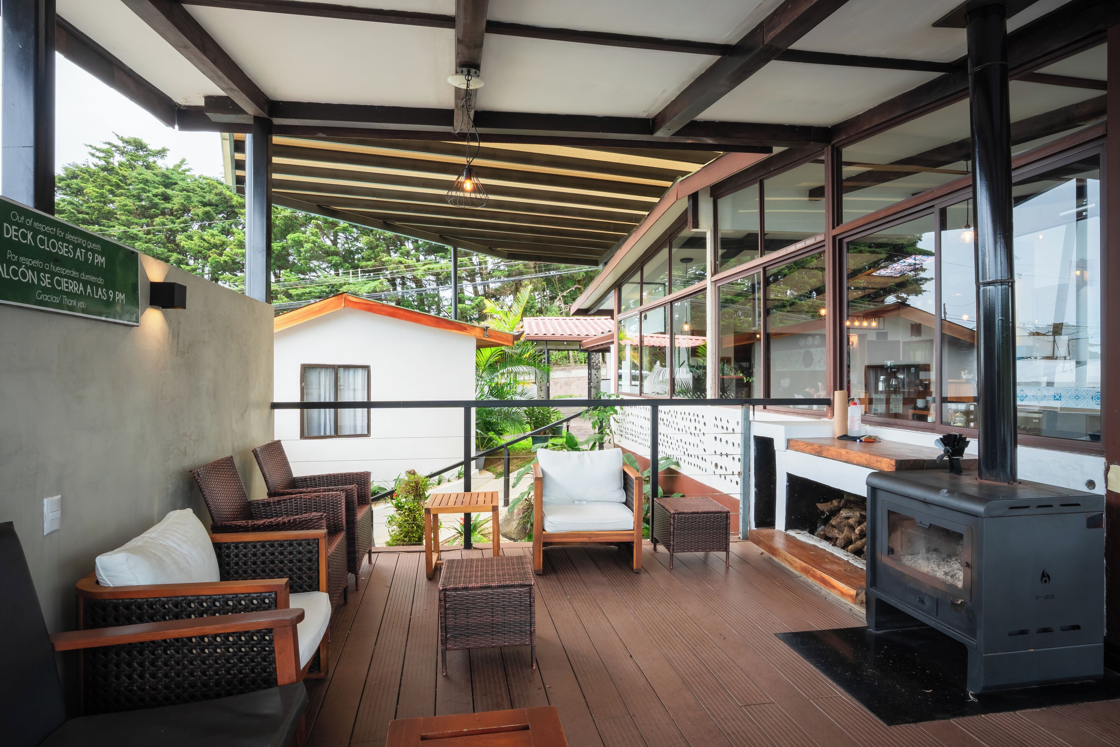 A covered outdoor seating area with wicker furniture, a fireplace, and a view of the surrounding landscape.