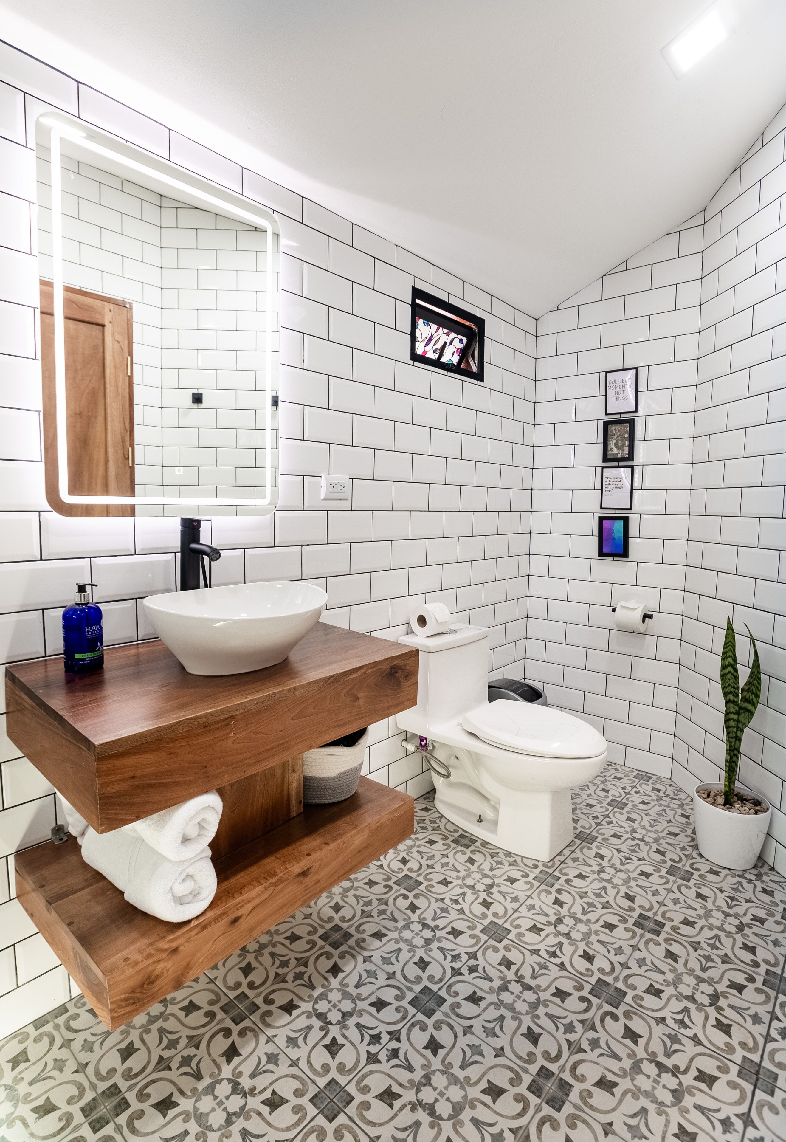 A modern bathroom with a white sink, wooden vanity, and a large mirror.