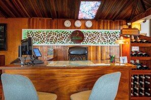 A wooden reception desk with a glass top, a clock, and a sign reading "FRONTERA".