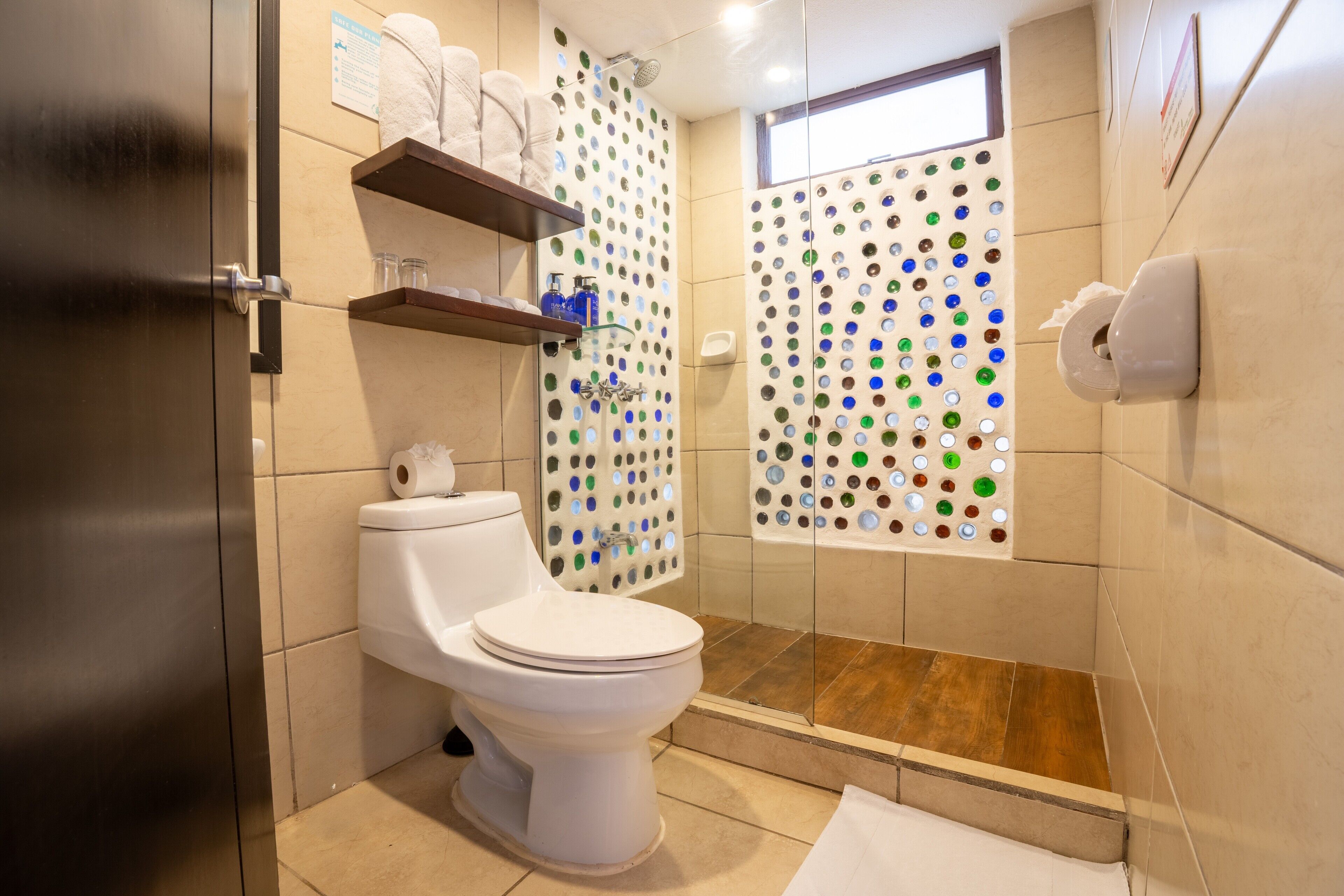 Een moderne badkamer met toilet, douche en een douchecabine met glazen wanden.
