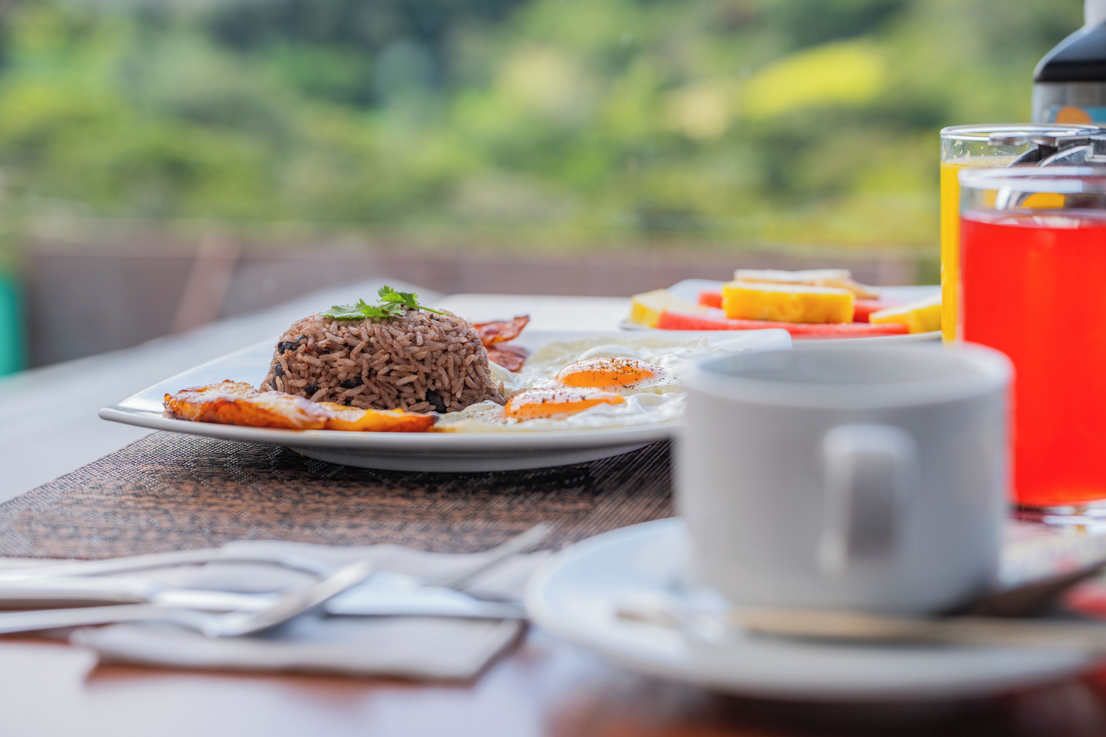 A breakfast setting with a plate of food, a cup, and a glass of red beverage.