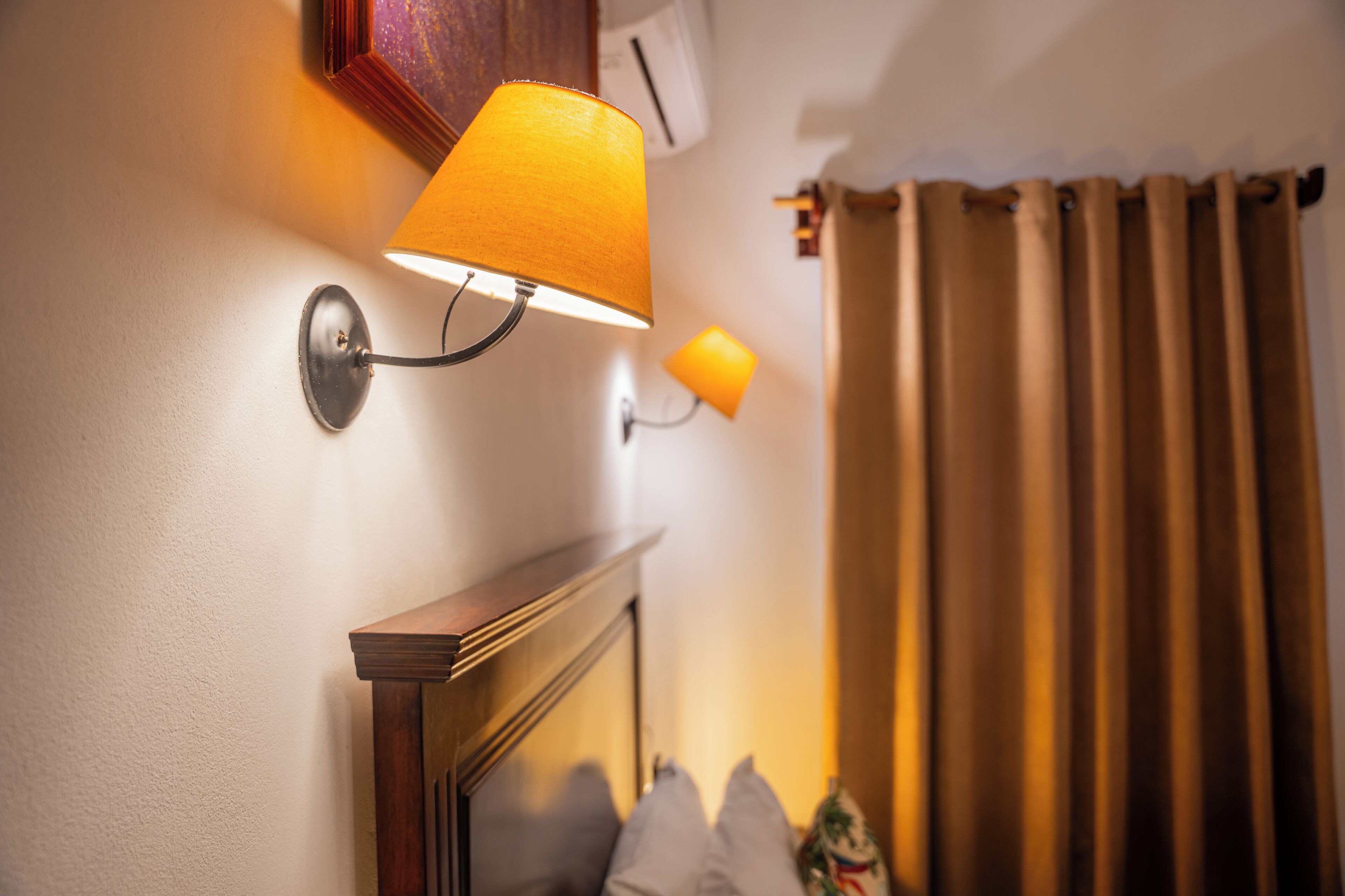 A wall-mounted lamp with a yellow shade, a wooden cabinet, and a curtain.