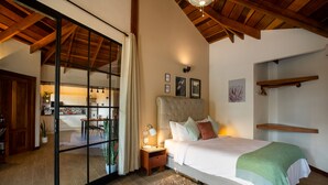 A bedroom with a large bed, a nightstand, a lamp, a green throw blanket, and a wooden ceiling.