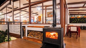 A cozy room with a wood-burning stove, large windows, and a wooden floor.