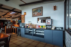A cafe with a bar area, a coffee machine, and shelves with various items.