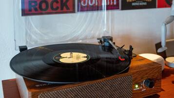 Een houten draaitafel met een vinylplaat, een bureaulamp en een muur met verschillende posters van rockbands.