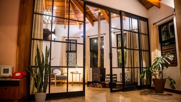 A room with a wooden ceiling, a fireplace, a potted plant, and a red telephone.