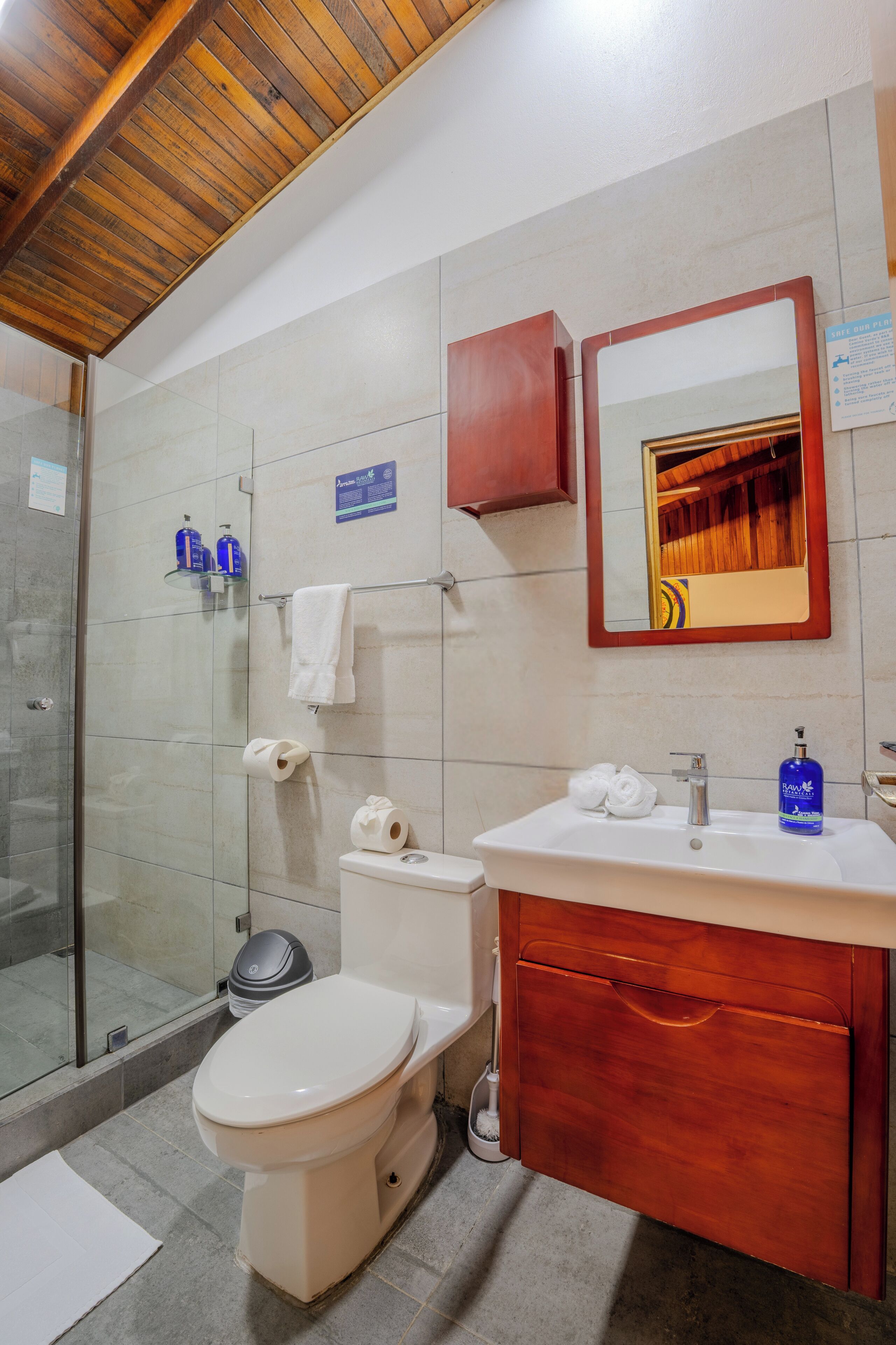 A bathroom with a toilet, sink, mirror, and shower area.