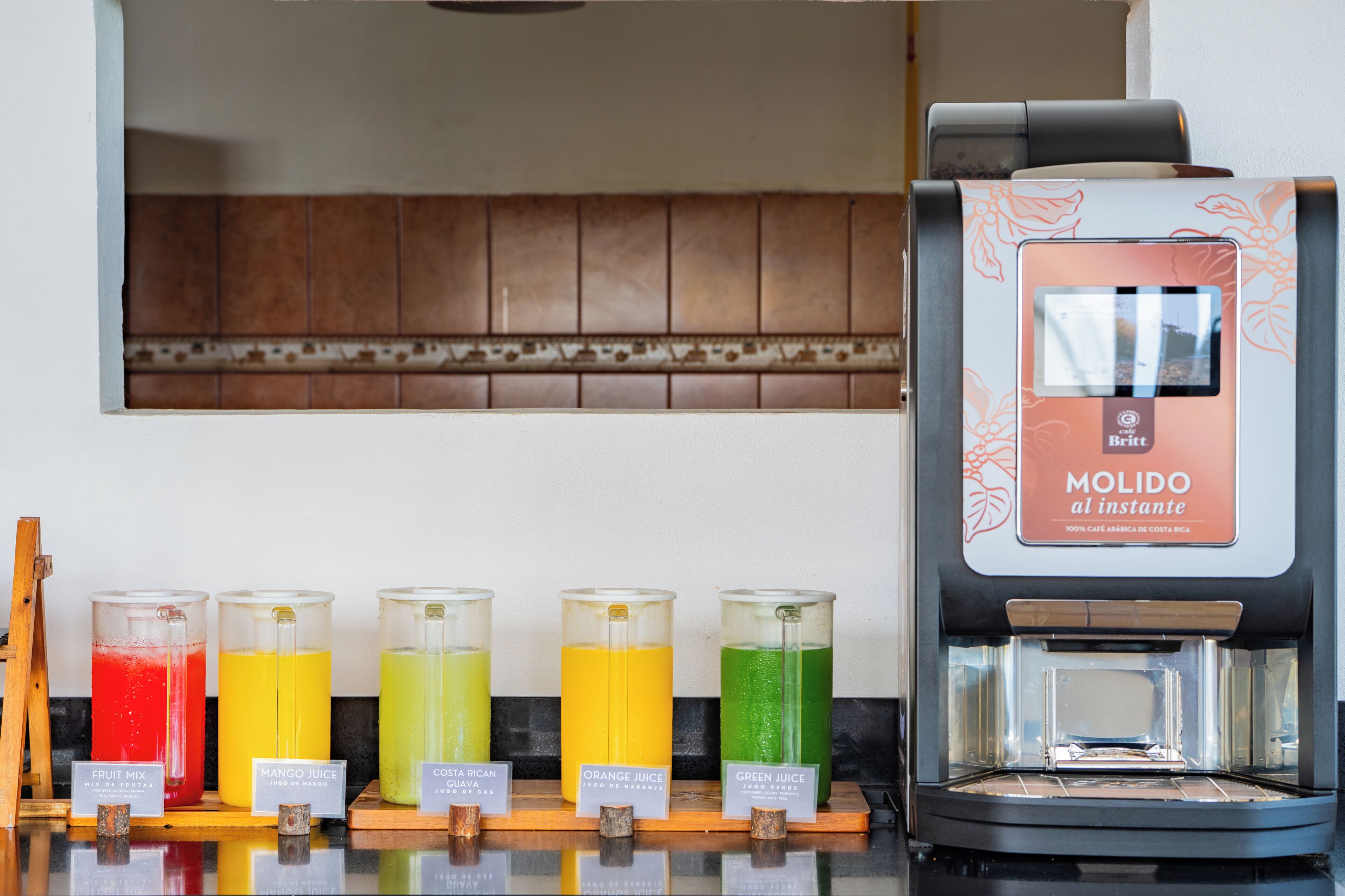 A coffee machine with a digital display and a selection of colorful beverages in front of it.