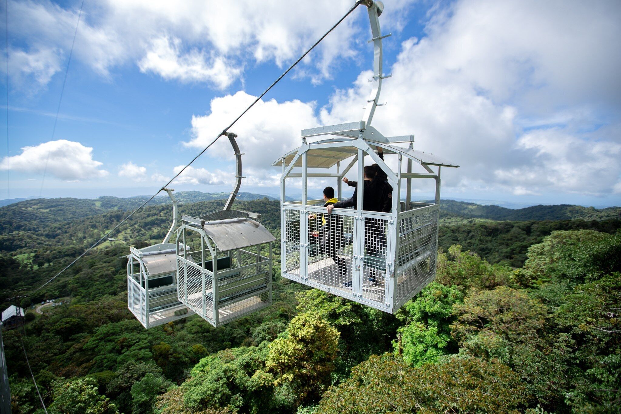 Un sistema de teleférico con pasajeros disfrutando de una vista panorámica de un paisaje boscoso y exuberante.